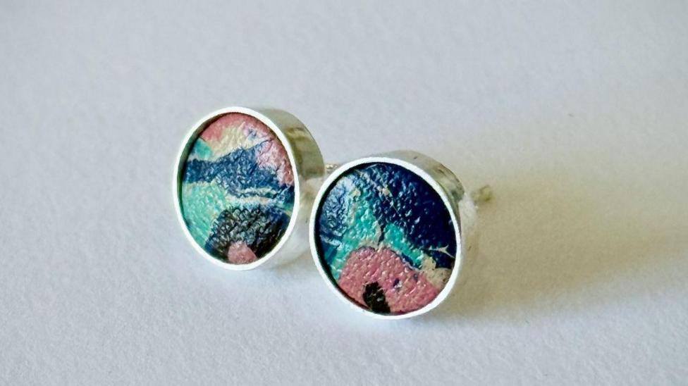 A pair of recycled silver stud earrings containing marbled leather from the ballet shoes in the centre